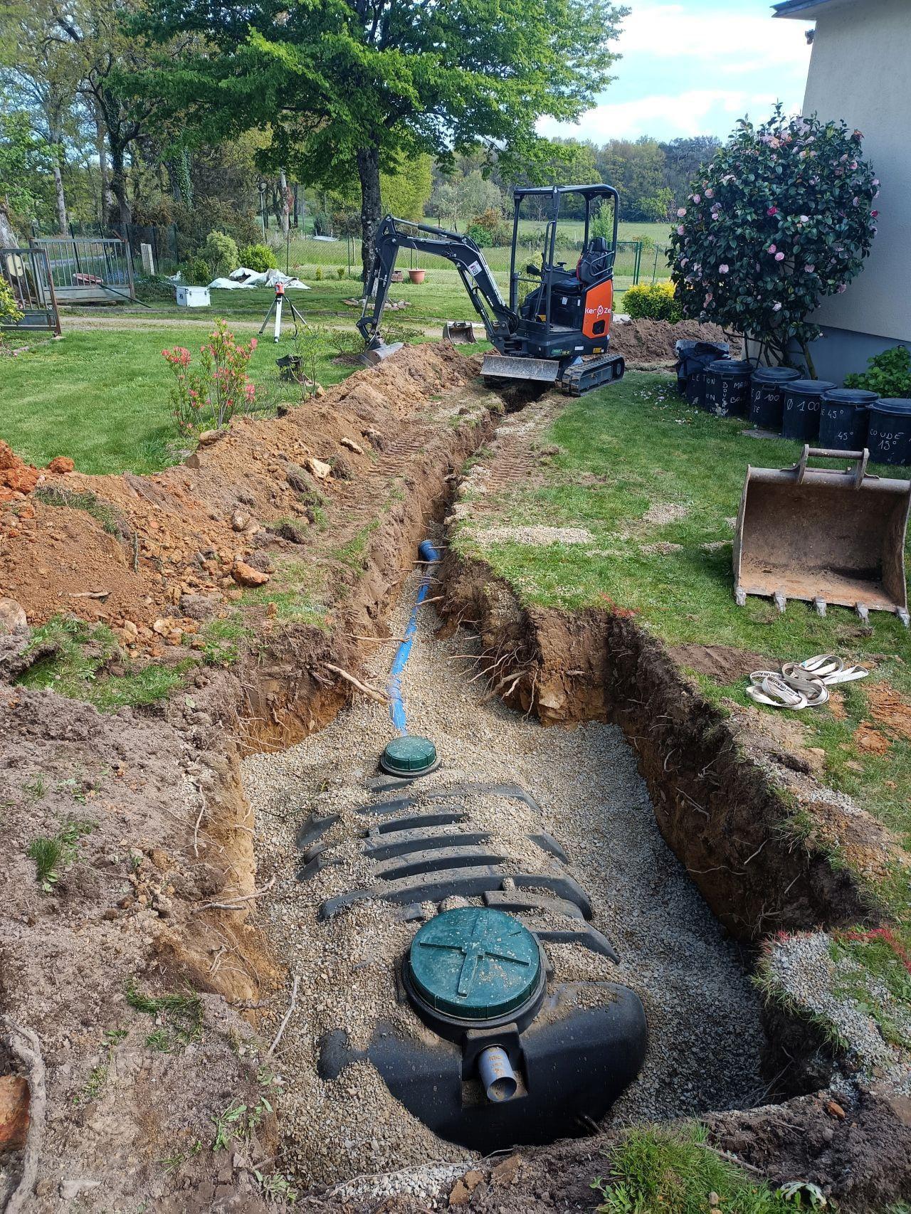 Photo d'une mini-pelle de chantier qui creuse une tranchée pour préparer l'installation d'une filière de traitement d'eaux usées.