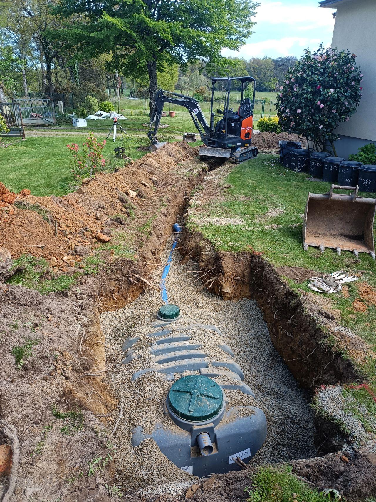 Photo d'une mini-pelle de chantier qui creuse une tranchée pour préparer l'installation d'une filière de traitement d'eaux usées.